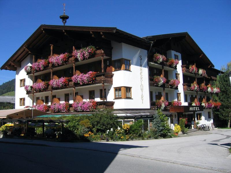 Hôtel traditionnel avec balcons en bois et fleurs colorées dans les jardinières sous un ciel clair.