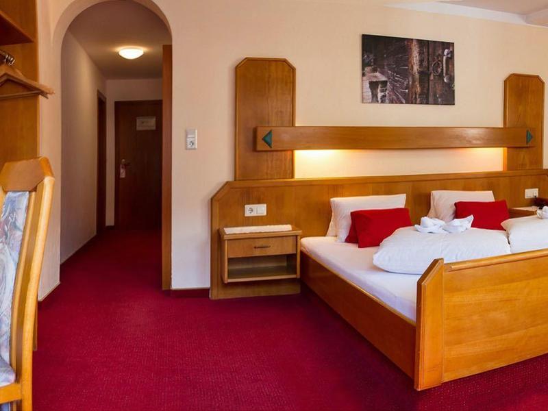 Chambre d'hôtel confortable avec lit double, télévision, bureau et tapis rouge.