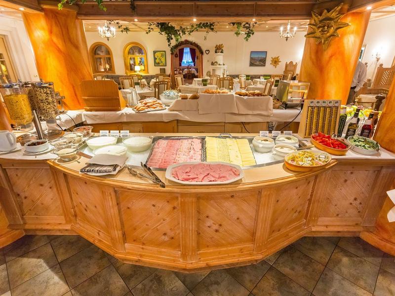 Buffet mit Wurstplatten, Käse und Tellern in einem warm beleuchteten Raum mit Holzmöbeln.