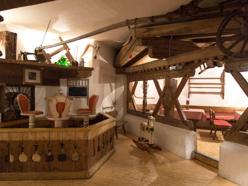 Rustikales Innenraumdesign mit Holzmöbeln, Weinflaschen, einem Weinfass und Sitzbereich mit Fenster.