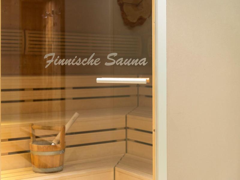 Innenraum einer finnischen Sauna mit hölzernen Sitzbänken und einem Wassereimer.