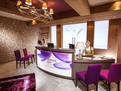 Reception moderna della hall dell'hotel con sedie viola, legno chiaro e illuminazione calda.