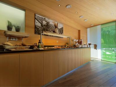 Area buffet con banco in legno, selezione di pane e bevande in interno hotel moderno