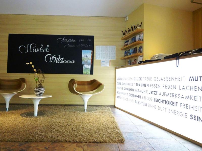 Modern hotel lobby with designer chairs, carpet, wine racks, and illuminated reception desk