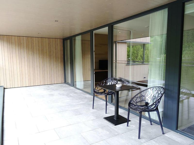 Modern balcony with table and two chairs next to large sliding glass doors.