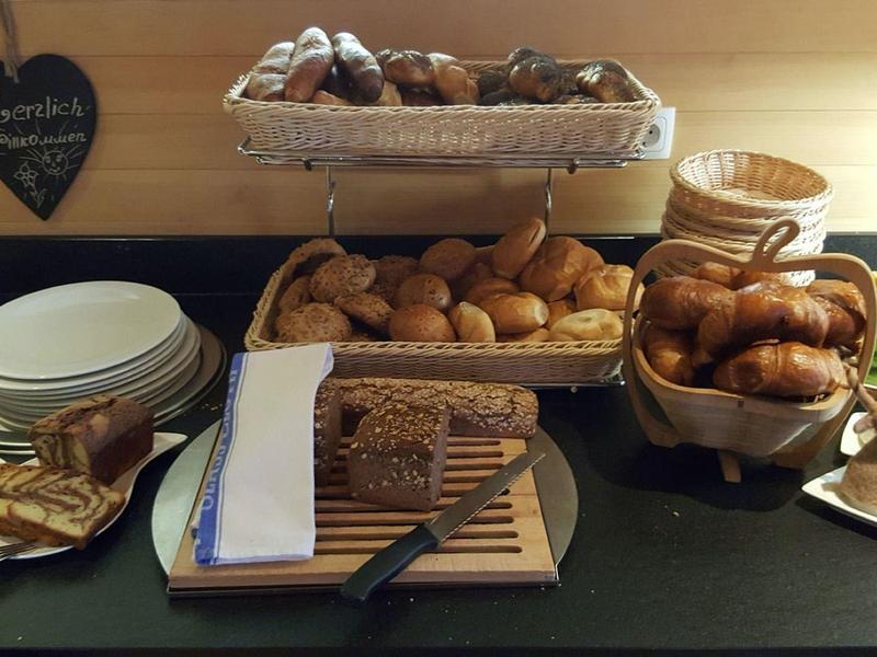 Various rolls and pastries on trays and plates with butter and jam.