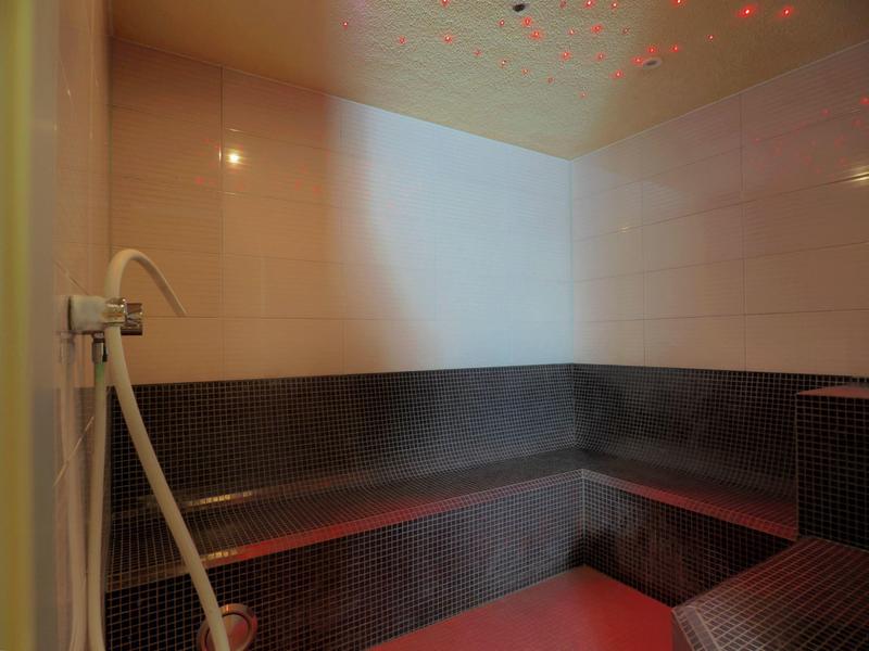 Steam sauna with dark tiles and wooden benches along the walls.