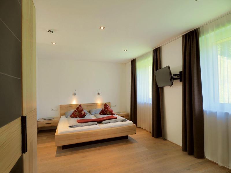 Modern hotel room with double bed, two windows, and wall-mounted TV.