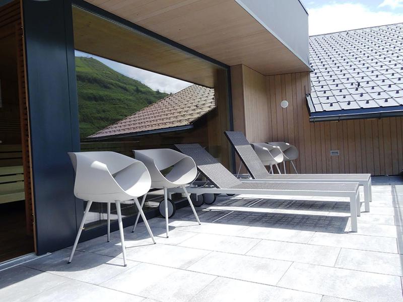 Terrace with modern white chairs and loungers at a mountain hotel.