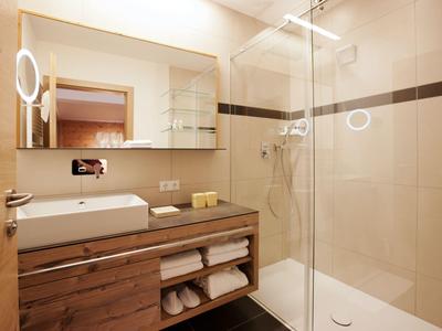 Bright bathroom with wooden vanity, mirror, and glass-enclosed shower.