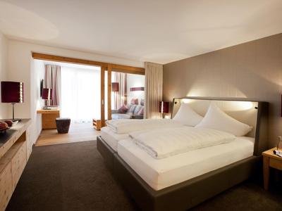 Modern hotel room with large bed, warm wood accents, and access to a balcony.