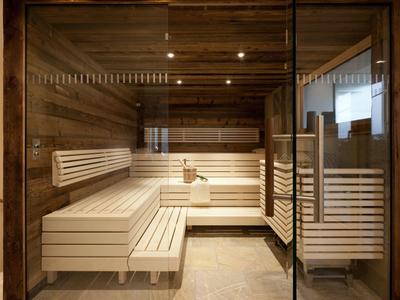 Modern sauna with light wood and glass walls in a wellness area.