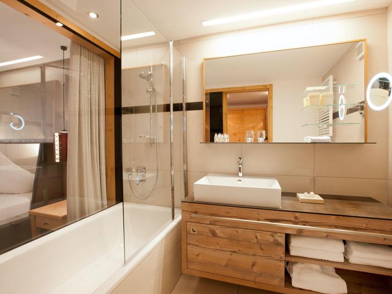 Modern bathroom with bathtub, glass partition, and wooden vanity with towels.