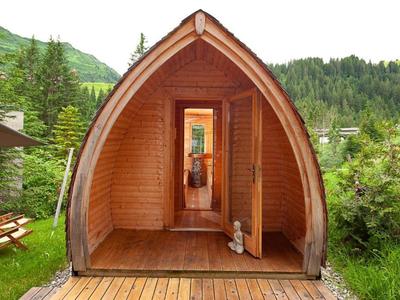 Gezellig klein houten hutje met open ingang in groene berglandschap.