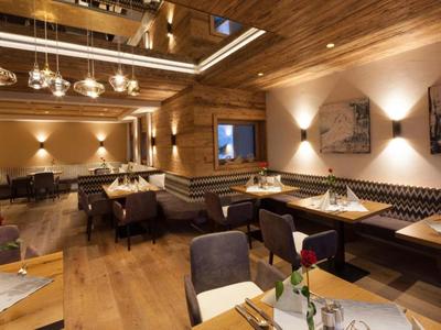 Gemütliches Restaurant mit Holzwänden, Decke, Tischen, Stühlen und warmem Licht.