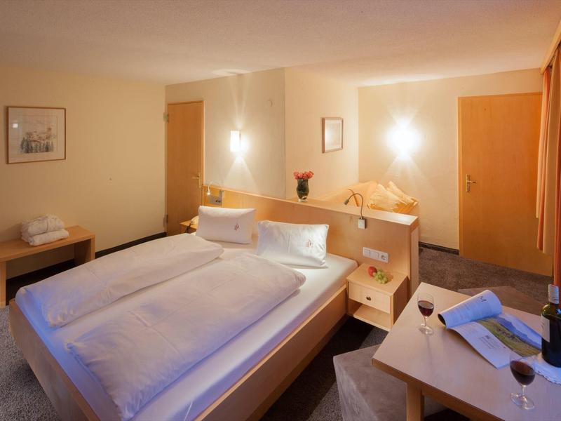 Gezellige hotelkamer met tweepersoonsbed, tafel, stoelen en warme verlichting.