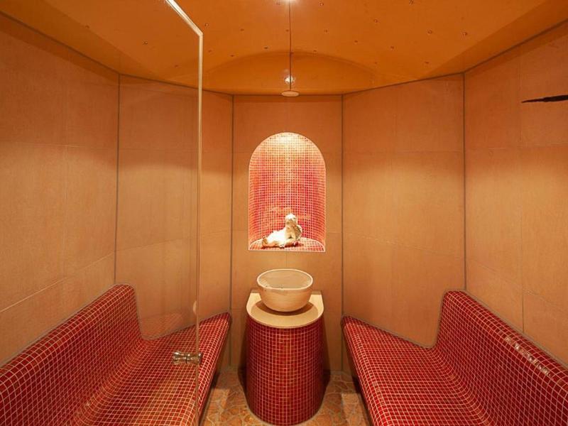 Gezellige zithoek met rode gevoerde banken en decoratief verlicht nisje.