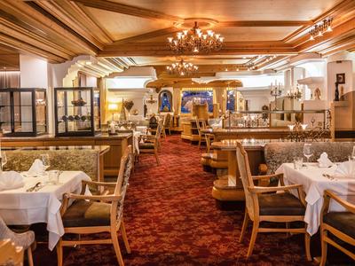 Elegant restaurant met gedekte tafels, rode tapijten en houten plafond