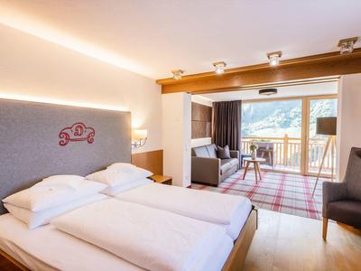 Hell eingerichtetes Schlafzimmer mit Doppelbett, Holzboden, Balkon und Bergblick.