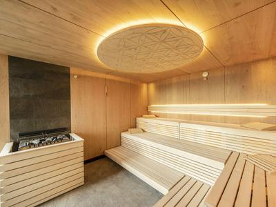 Moderne sauna met houten bekleding, gelaagde houten banken en indirecte plafondverlichting.