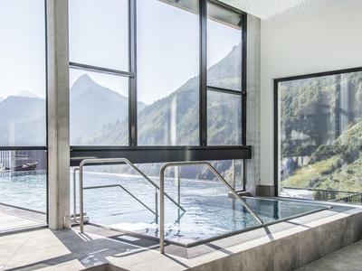 Moderne wellnessruimte met groot bubbelbad en panoramische ramen met uitzicht op de bergen.