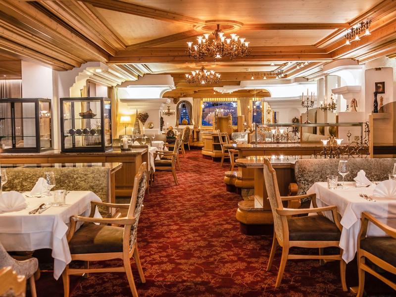 Gemütliches Restaurant mit Holzbalkendecke, eleganten Stühlen, weißen Tischdecken und rotem Teppich.