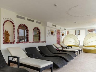 Moderní relaxační místnost s černými a bílými lehátky a kulatými sezeními u zdi.