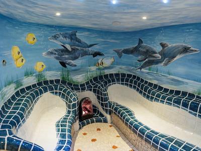 Koupací prostor s mozaikovými lavicemi a nástěnnými malbami delfínů a tropických ryb.