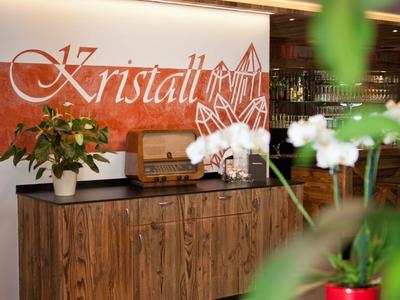 Réception moderne avec comptoir en bois, plantes et enseigne lumineuse 'Kristall'.