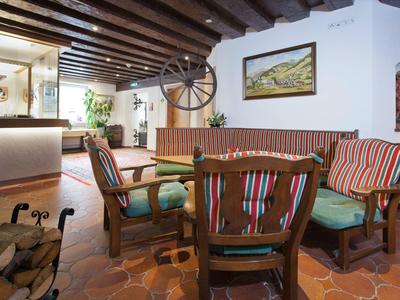 Accogliente area lounge dell'hotel con mobili in legno e cuscini colorati su pavimento in terracotta.