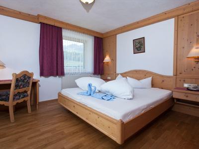 Camera d'hotel accogliente con letto matrimoniale, mobili in legno e scrivania vicino alla finestra