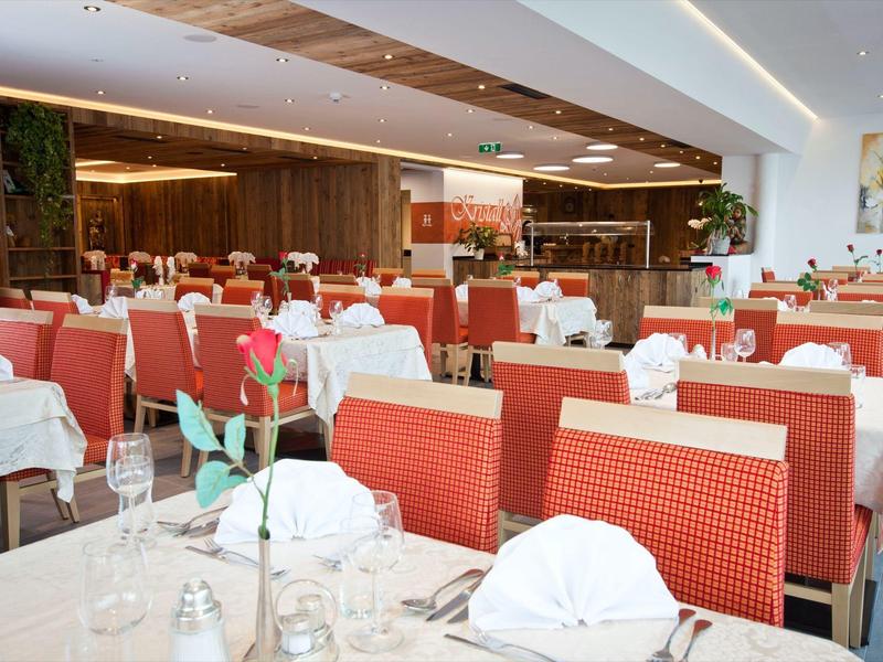 Elegancka restauracja z nakrytymi stołami i czerwonymi krzesłami, idealna dla gości hotelowych.