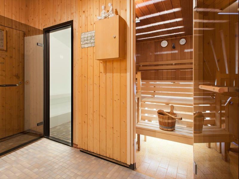 Nowoczesne wejście do sauny z drewnianymi ścianami i szklanymi panelami.