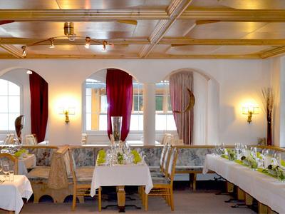 Elegant restaurant with white tablecloths, floral patterned chairs, and large windows with curtains.