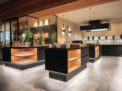 Modern hotel bar with wooden ceiling, dark wood counters, and warm lighting.