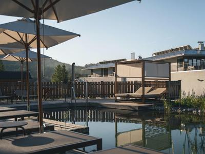 Modern outdoor pool area with sun loungers and large umbrellas at a quiet hotel.