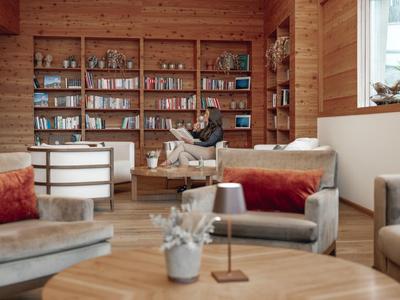 Cozy reading corner with wooden walls and shelves full of books in a hotel lounge.