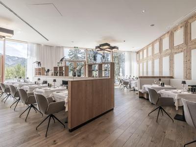 Licht modern restaurant met houten vloeren, comfortabele stoelen en grote ramen met uitzicht op de bergen.