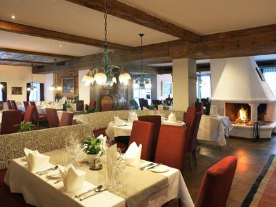 Ristorante luminoso con tavoli apparecchiati, sedie rosse e un camino aperto sullo sfondo.