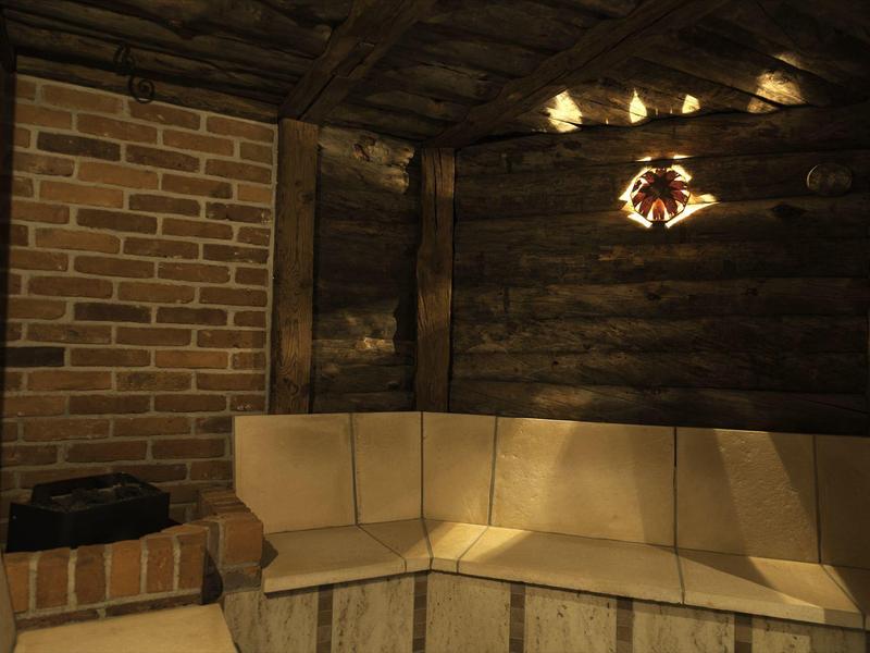 Przytulna sauna z drewnianymi ścianami, ceglanym narożnikiem i tapicerowanym siedziskiem.