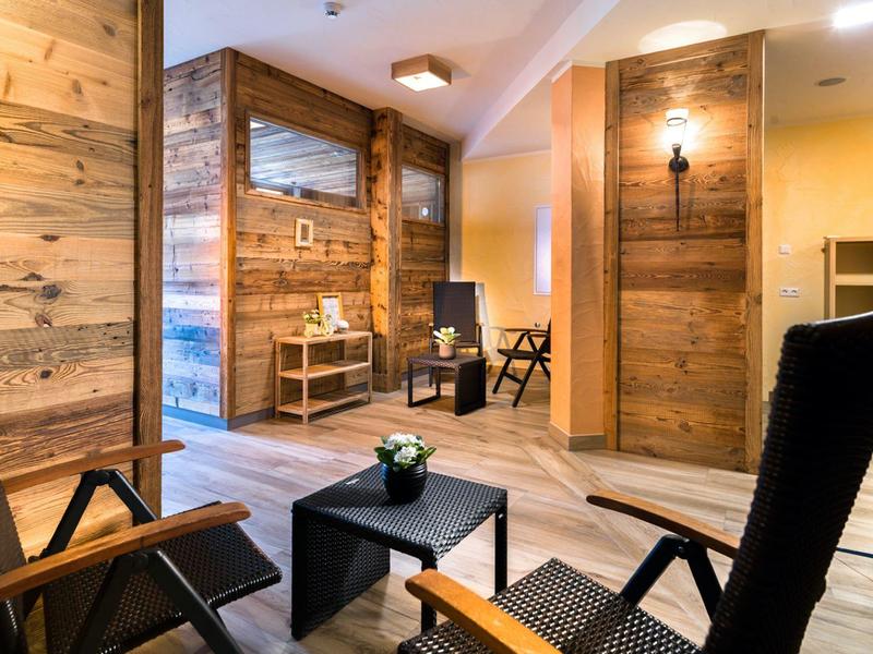 Pohodlná odpočinková místnost sauny s dřevěným obložením, lehátky a malým stolkem s rostlinou.