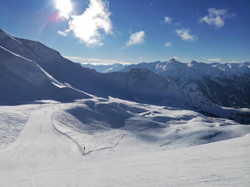 Zasněžená horská krajina s jasnou modrou oblohou a slunečním světlem.