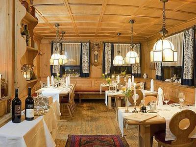 Ristorante rustico con pareti in legno, tavoli in legno, sedie e atmosfera calda.