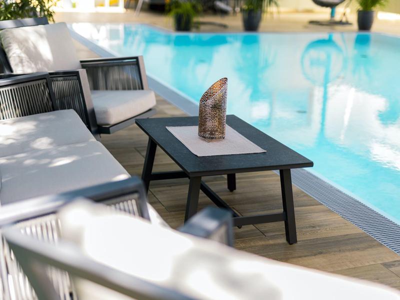 Comode poltrone lounge accanto a una piscina con terrazza in legno e tavolo con decorazione.