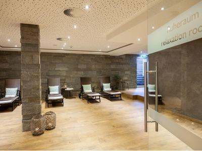 Moderner Ruheraum mit bequemen Liegen, Natursteinwänden und hellem Holzboden.