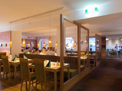 Interiér moderní restaurace s dřevěným nábytkem a prostřenými stoly.