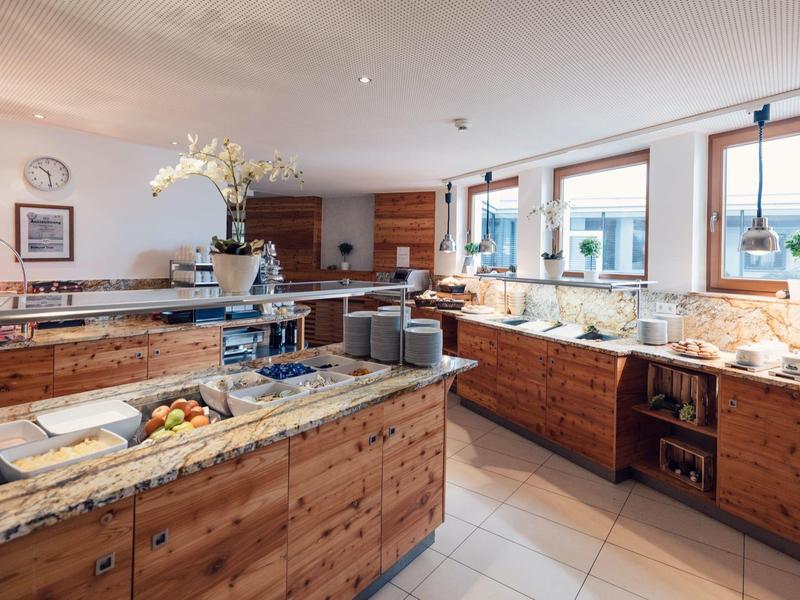 Moderne helle Küche mit viel Holz, Granit-Arbeitsplatten, großen Fenstern und einer Kochinsel.