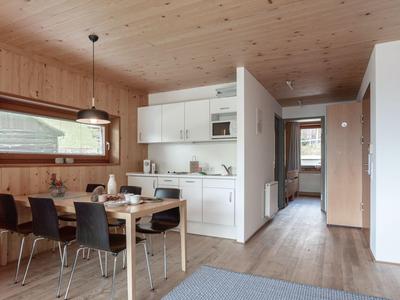 Zona pranzo e cucina moderne con pareti e pavimento in legno in una casa vacanze.