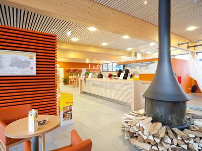 Hall d'hôtel moderne avec cheminée, réception et espaces assis confortables.