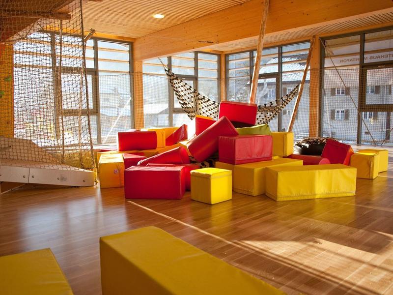 Cozy seating areas with red and yellow cushions in a bright room with large windows.
